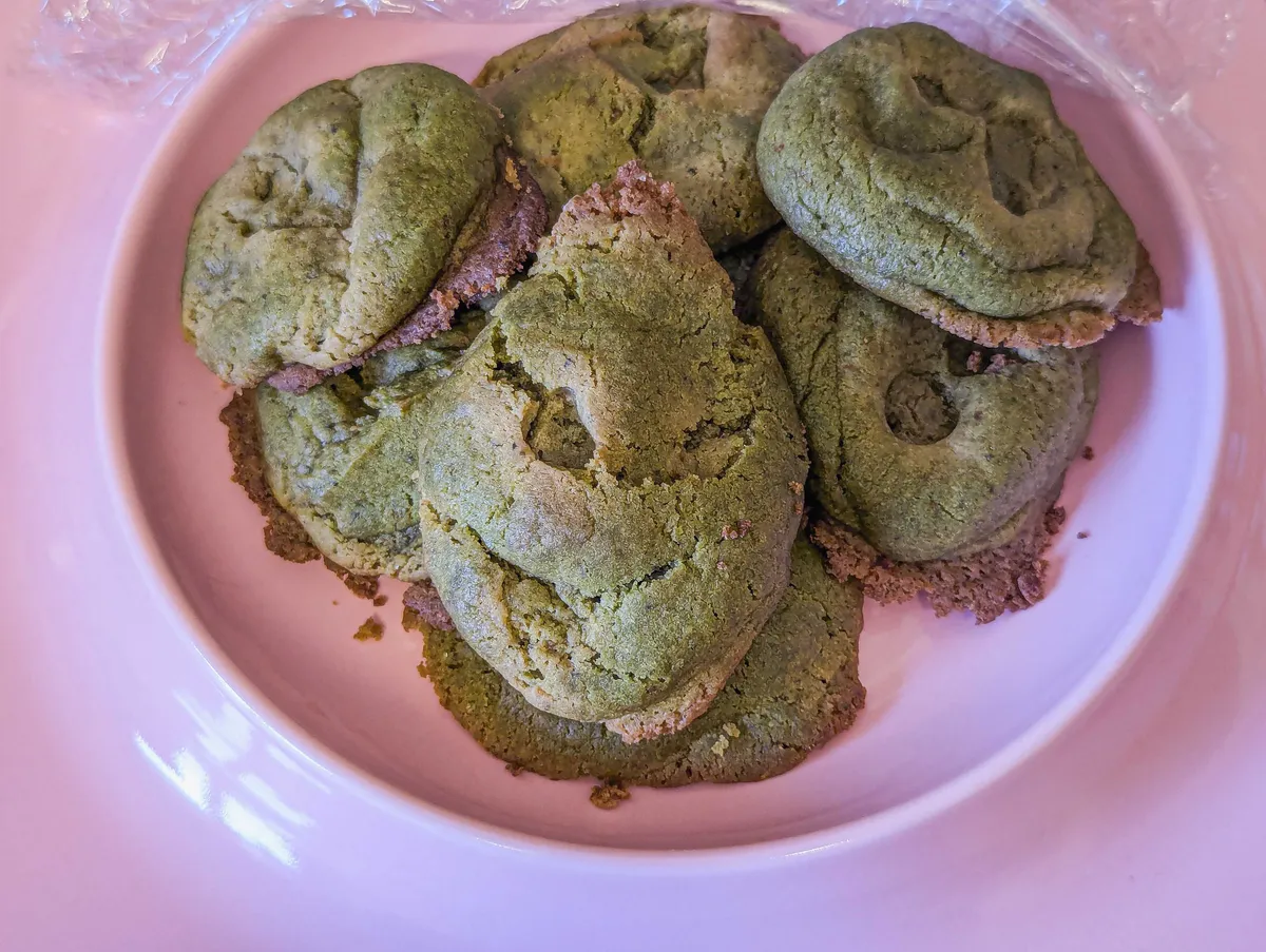 A plate of questionably-shaped cookies, with the top one looking like the Grinch.