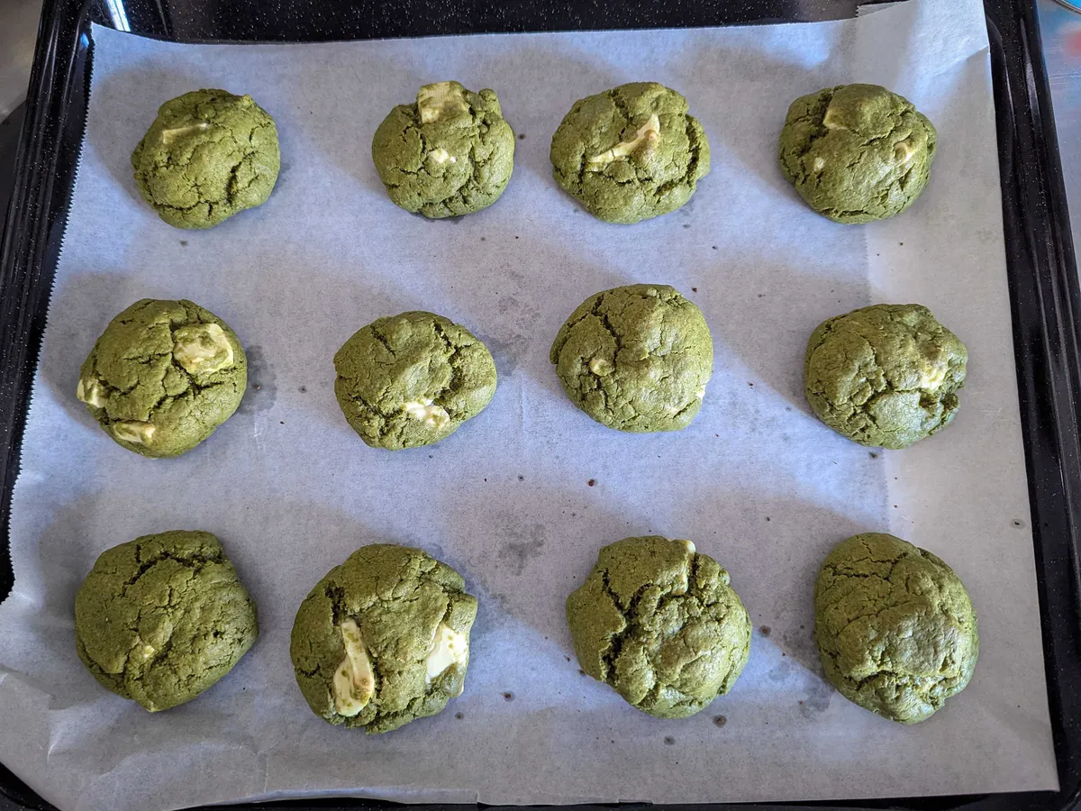 12 crinkly green cookies (4 in a row) with large chunks of white chocolate.