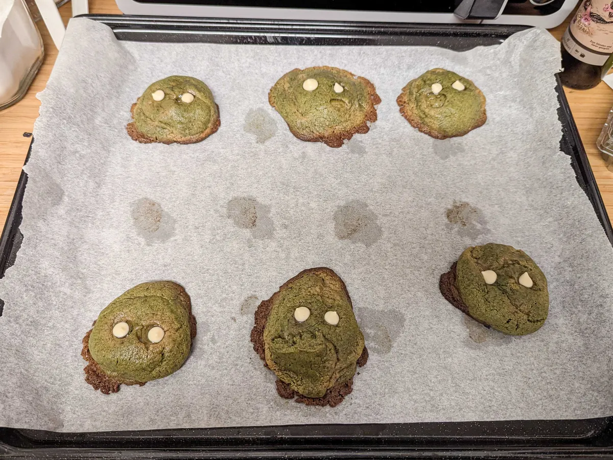 6 green cookies with two white chocolate chips placed on each to represent eyes.