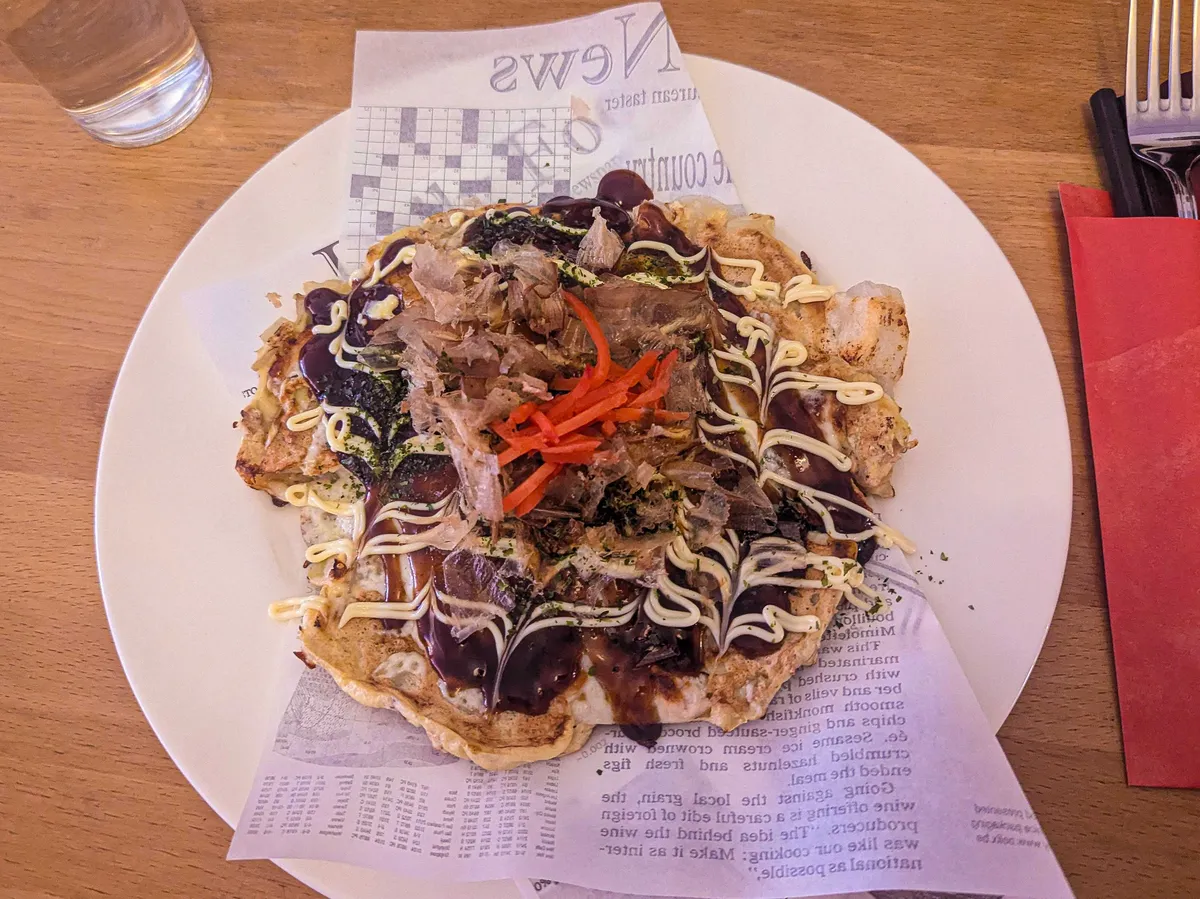 A plate of okonomiyaki with the signature mayonnaise design. There's also bonito flakes and pickled ginger.