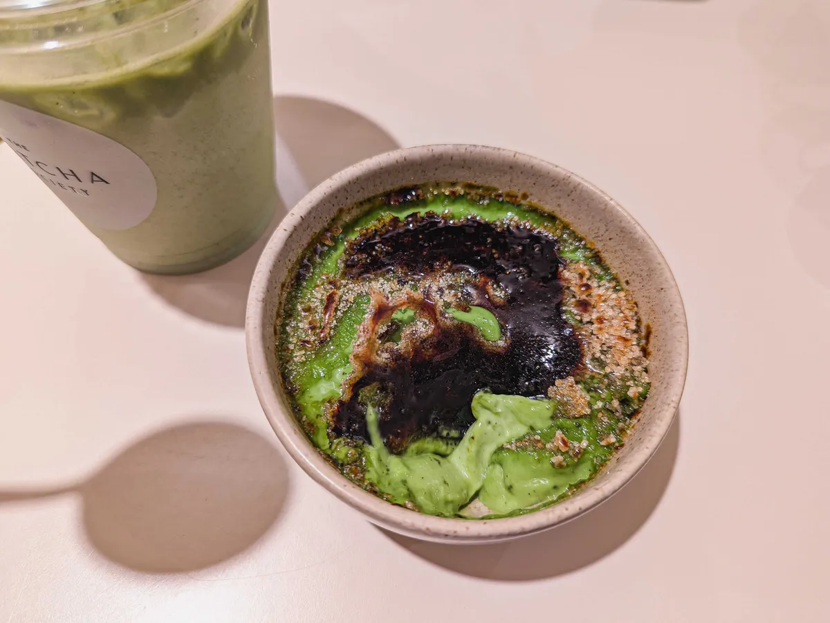 A matcha crème brûlée that's been poorly constructed. There are still sugar crystals on the side and some spots without any sugar at all. The center has been burnt to a blackened crisp.