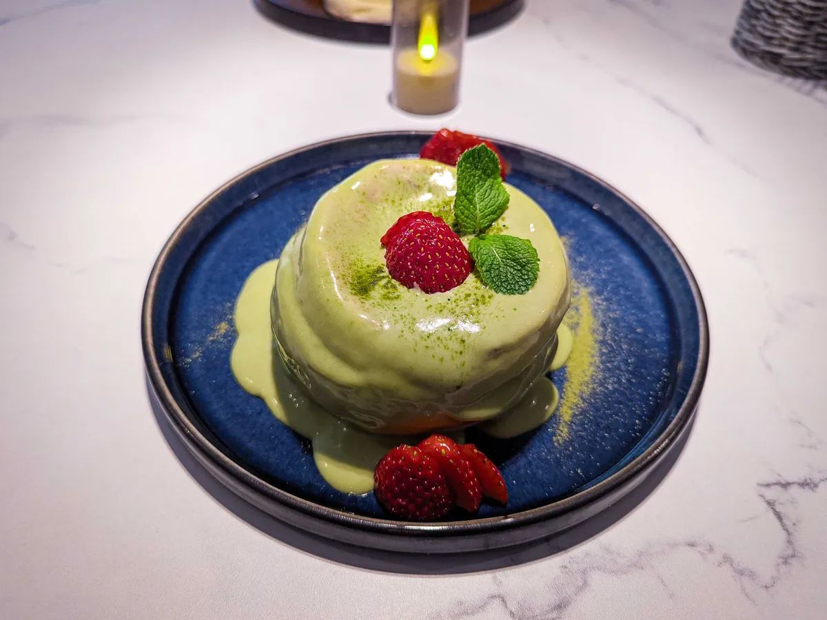 A soufflé pancake smothered in matcha crea and topped with berries.