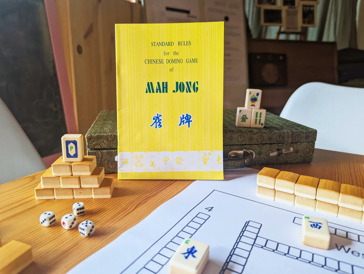 An old mahjong game displayed to show the yellow instruction book and bamboo details of the mahjong blocks.