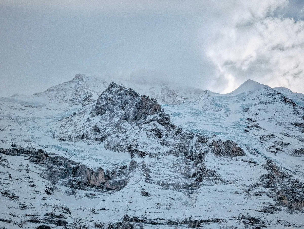 Stony mountain ridges covered in snow and some parts are frozen into light blue ice.