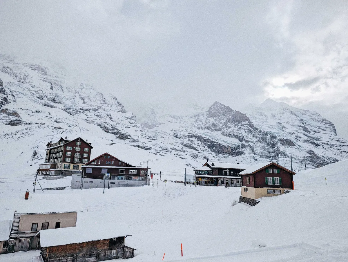 6 brown buildings scattered amongst the snow.