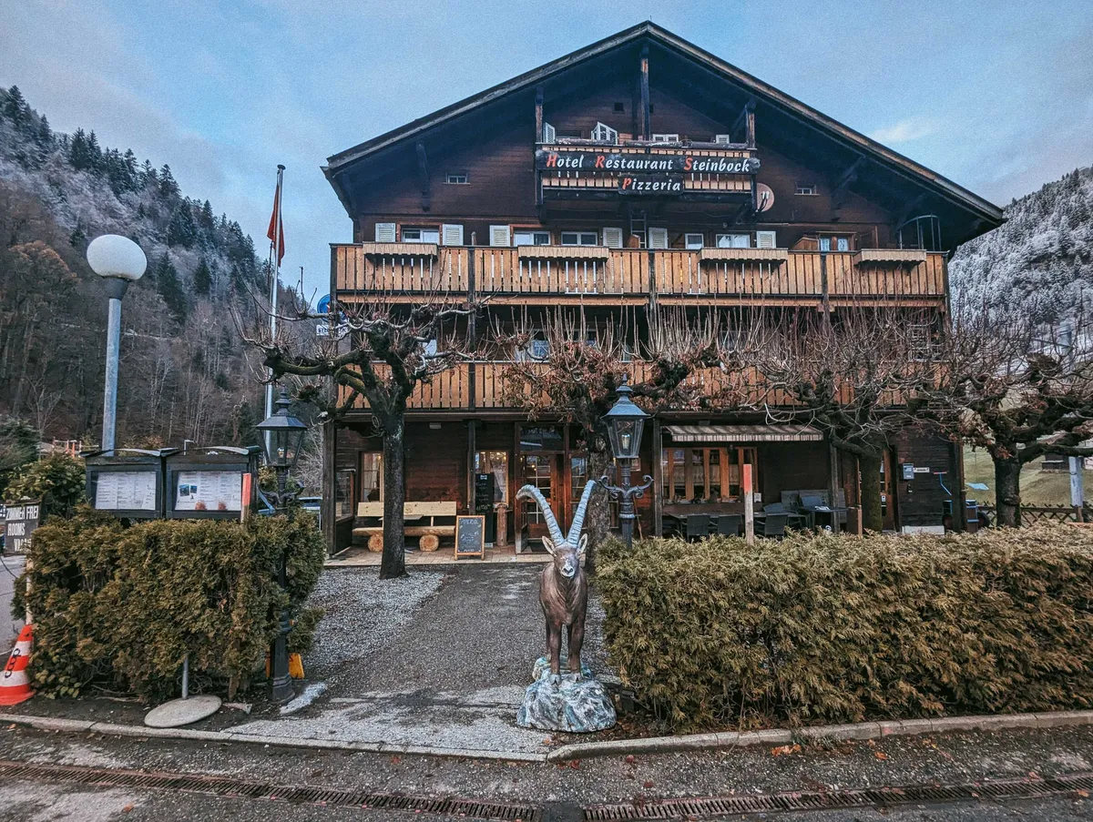 A typical wooden chalet-style restaurant with a statue of an alpine ibex by the entrance.
