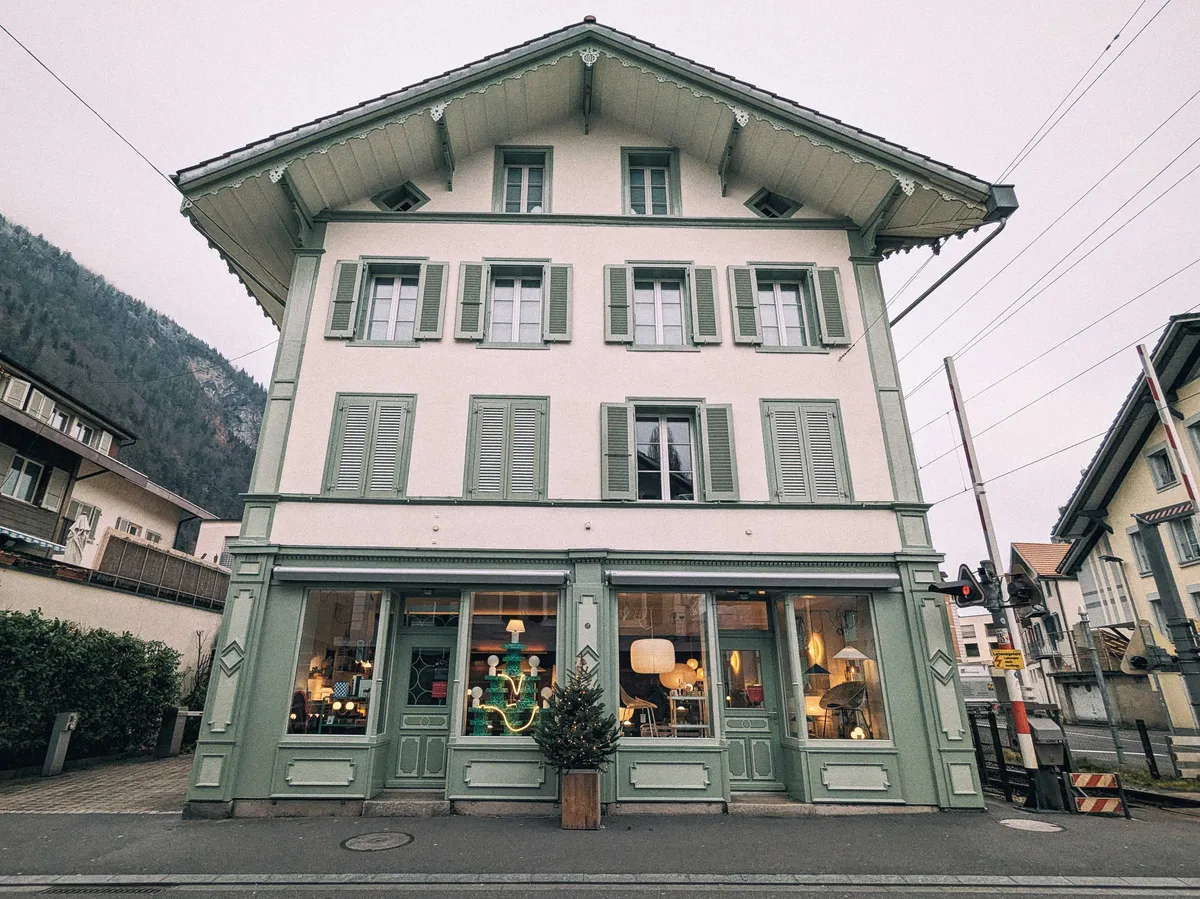A traditional house-shaped building with white walls and seafoam green details on the windows and framing.