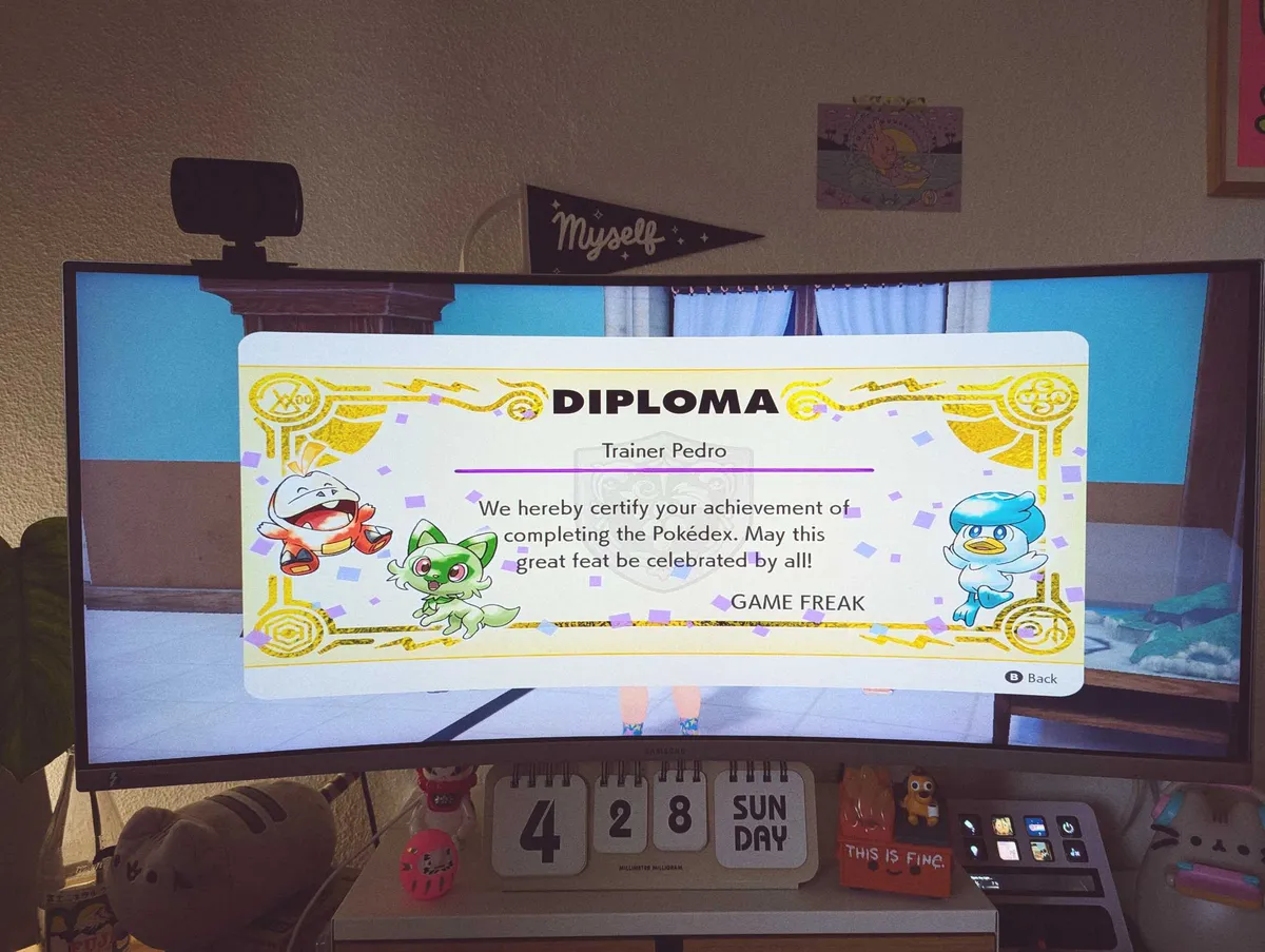 A monitor displaying a "diploma" on the screen that congratulates the player for completing their Pokédex.