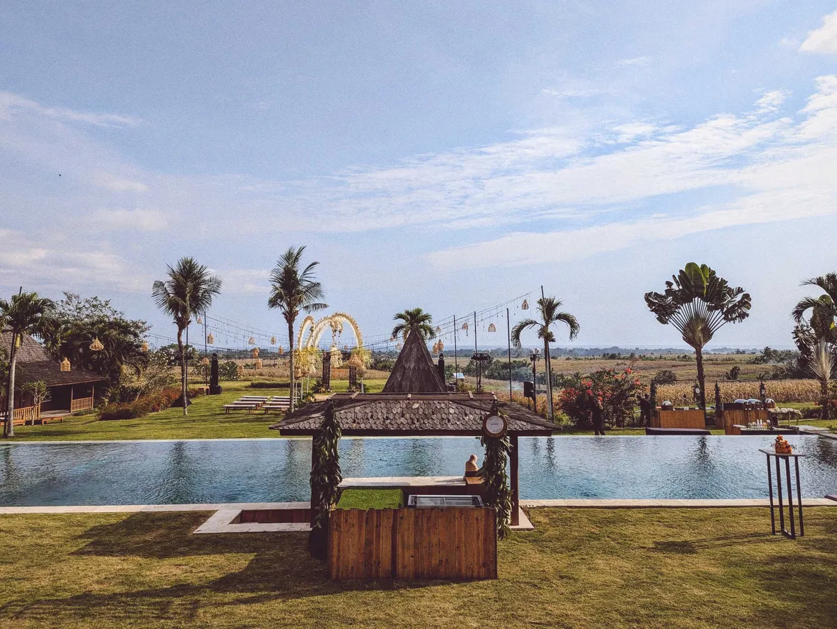 A Bohemian-inspired wedding in the middle of rice fields. There is a pool in front, which adds beachy vibes to the photo.