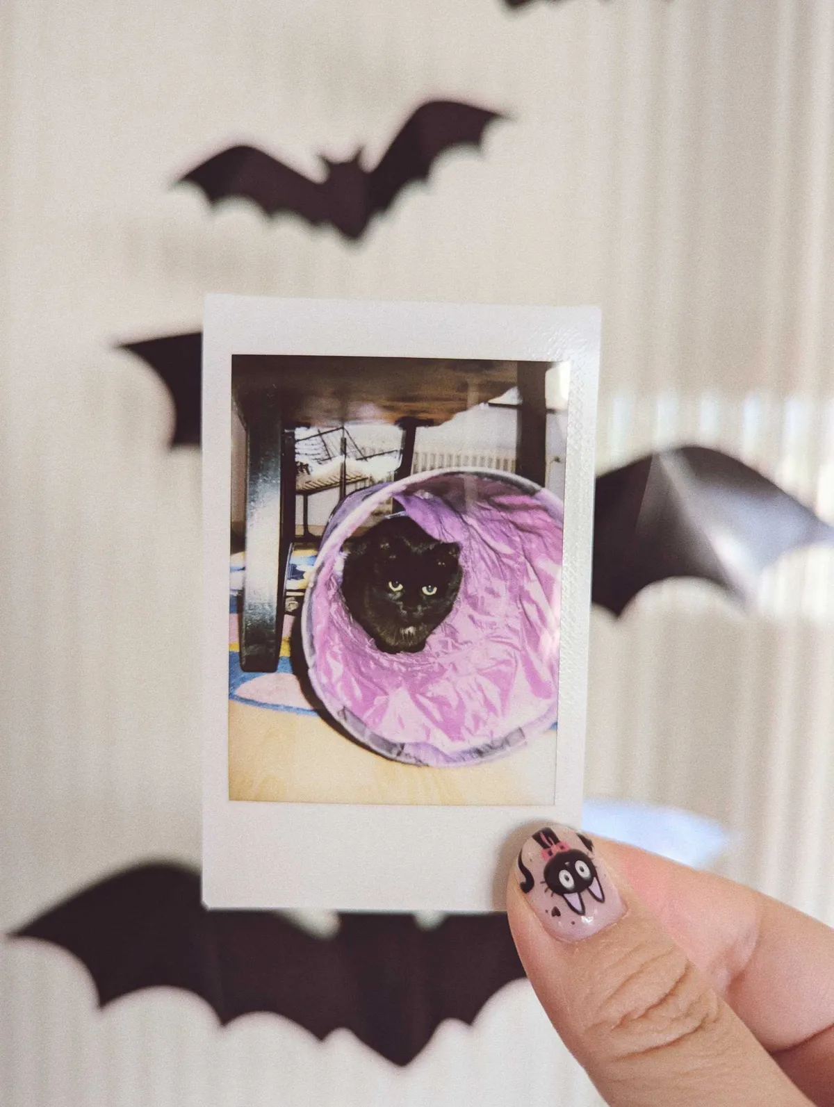 Peige holding a polaroid of Boba sitting inside a purple tunnel.