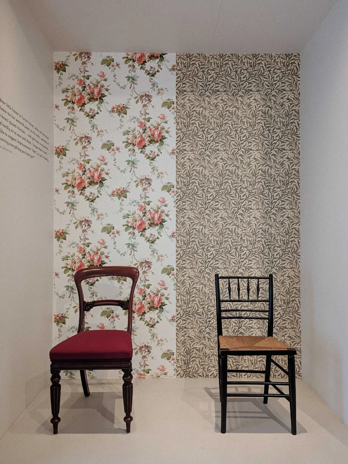 Two chairs of different styles set against two different wallpapers. The left chair has a red velvet seat with a dark wooden frame. It's set against a pink and green floral wallpaper. The right chair has a woven jute seat with a black wooden frame. It's set against a leafy green wallpaper.