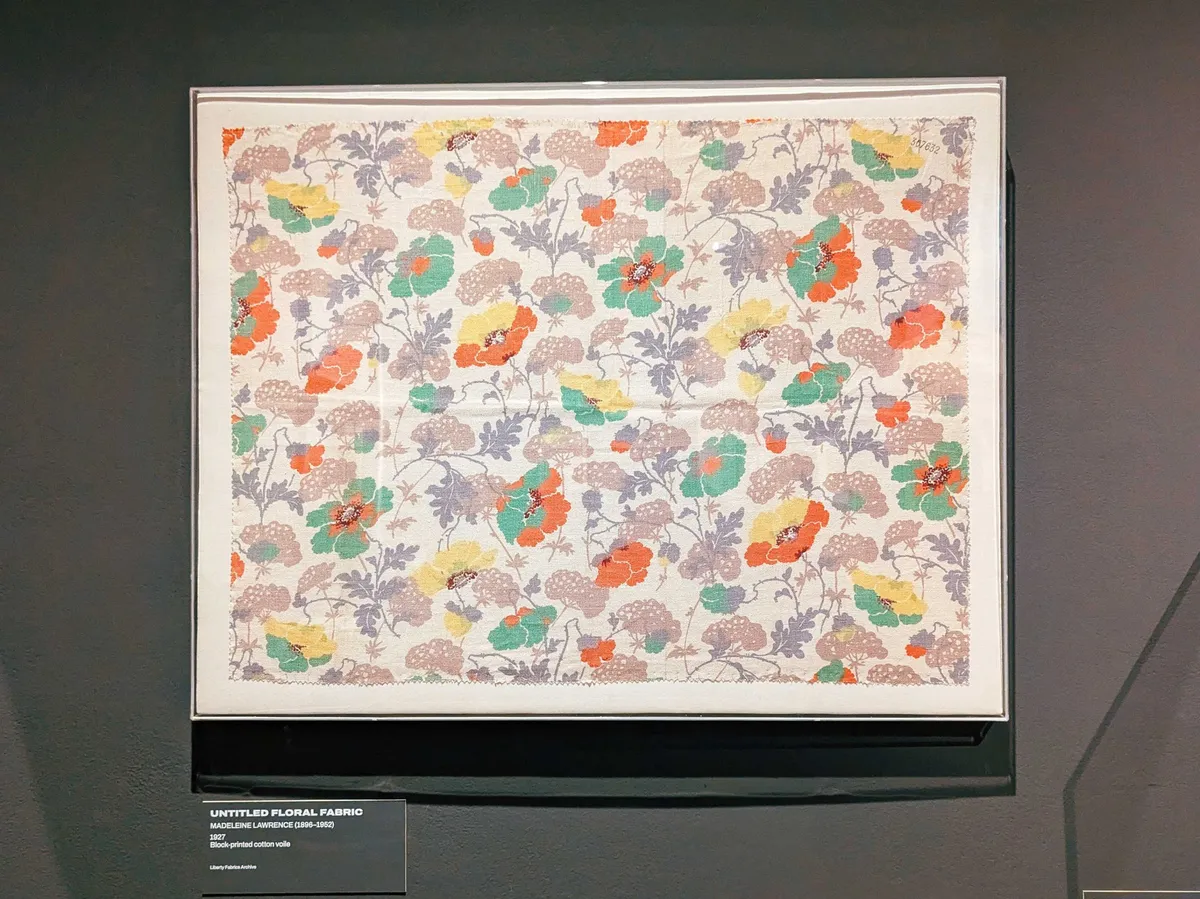 A floral pattern with bold yellow, orange, and green flowers, complimented by softer beige and grey-toned leaves.