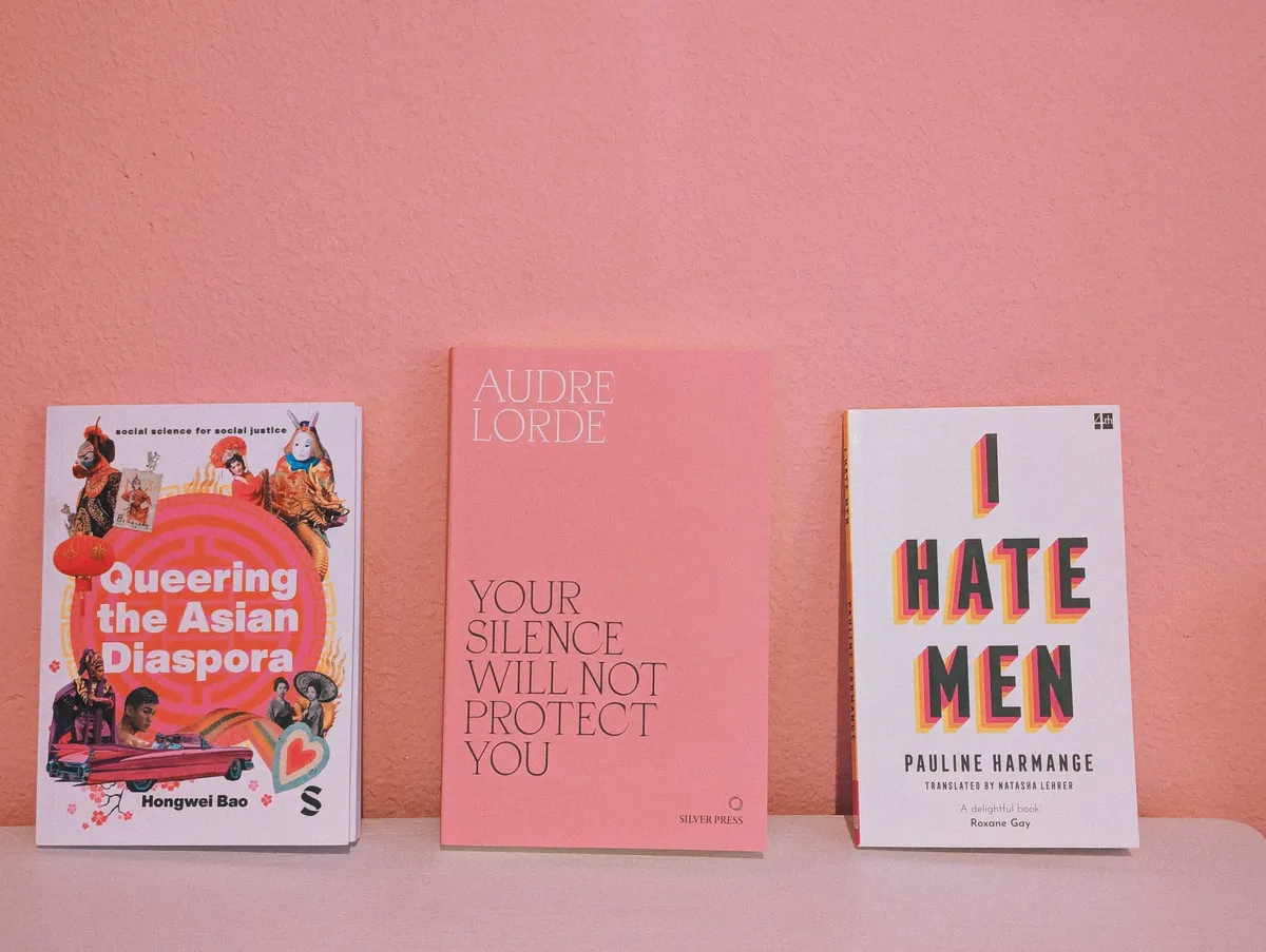 3 books against a pink wall: "Queering the Asian Diaspora," "Your Silence Will Not Protect You," "I Hate Men."