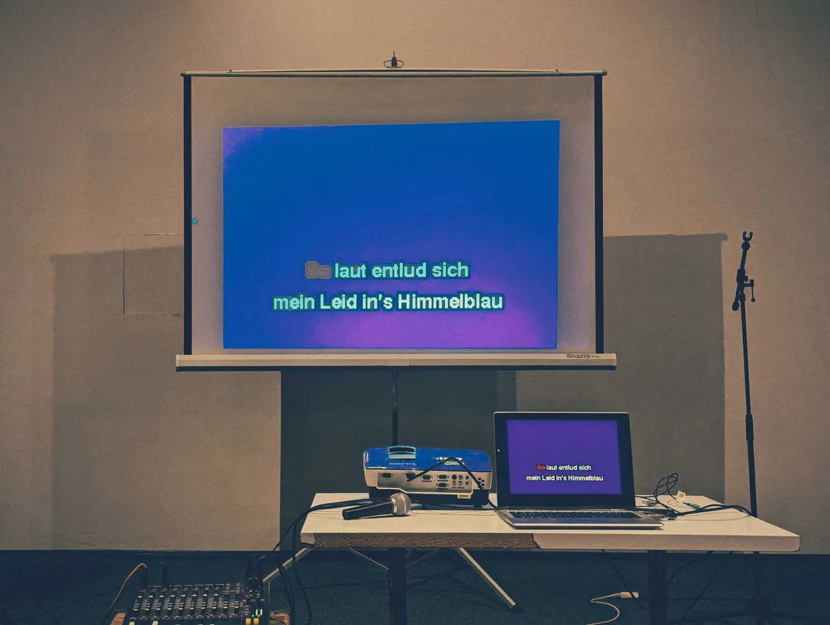 Karaoke lyrics on a projector screen in German.