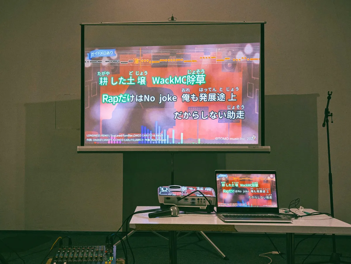 Karaoke lyrics on a projector screen in Japanese.