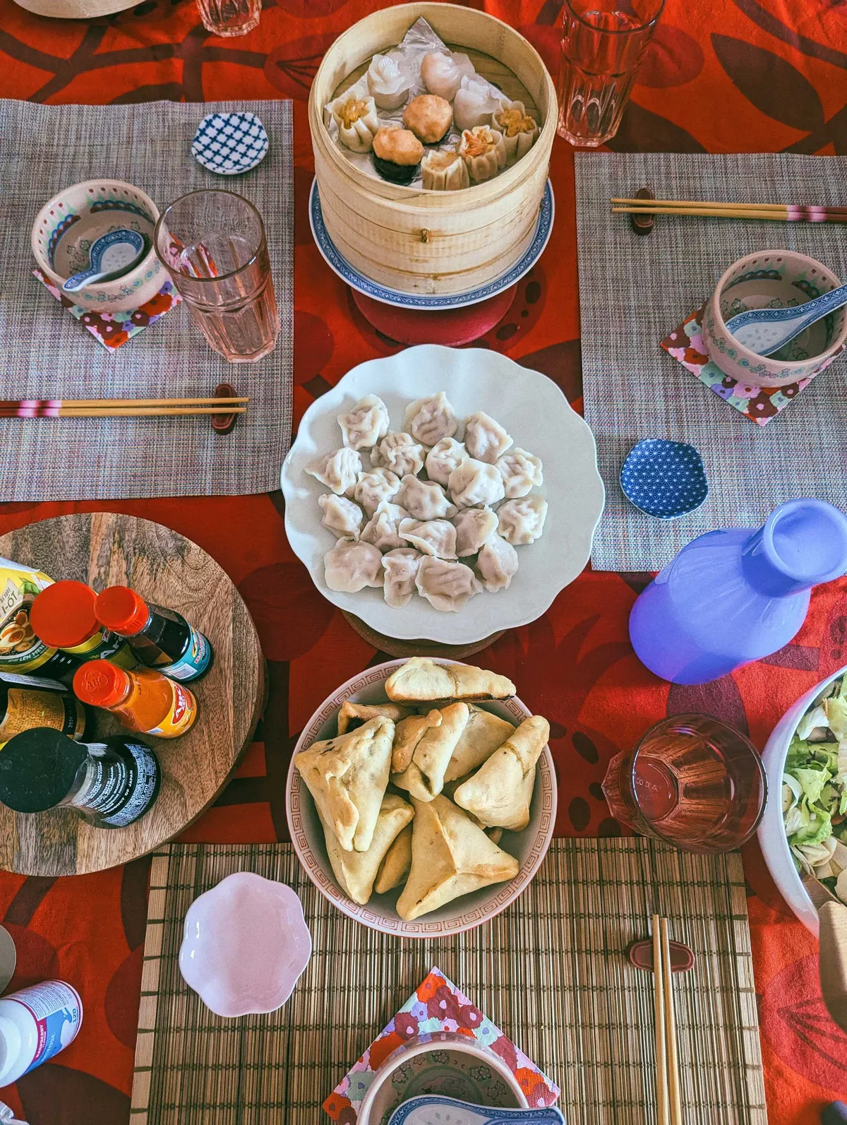 A table spread containing the food listed in the caption, against a red tablecloth.