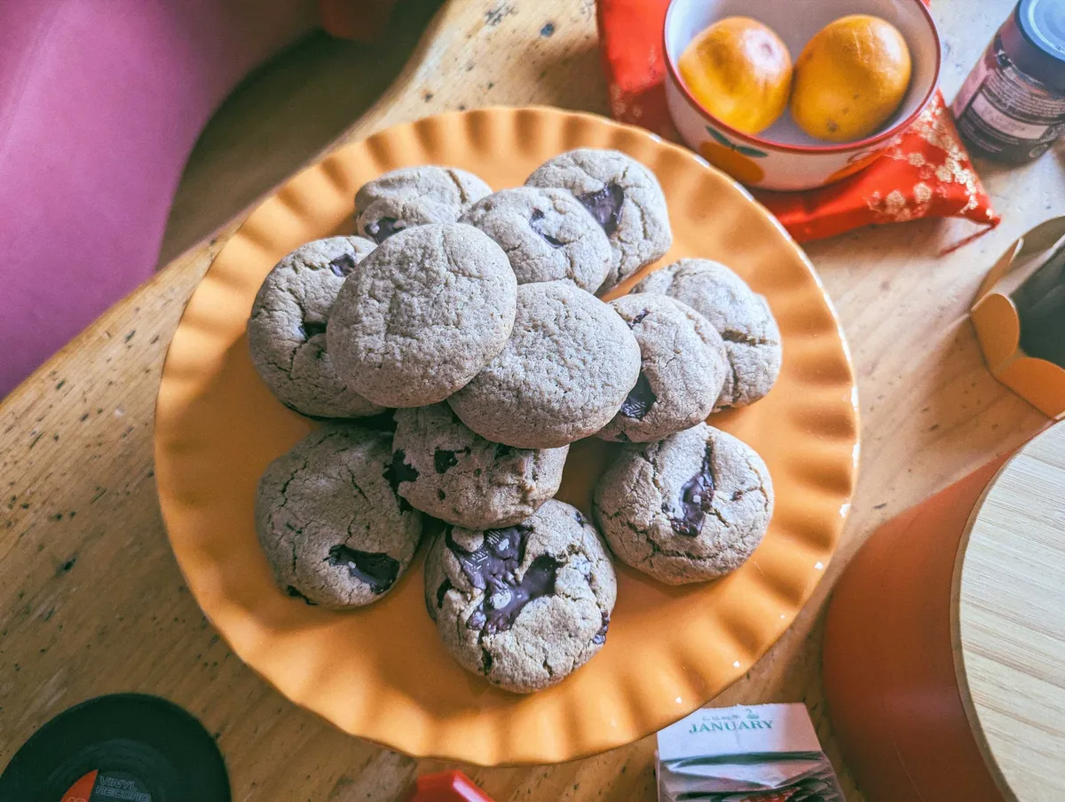 A stack of chocolate chip cookies on an orange plate.