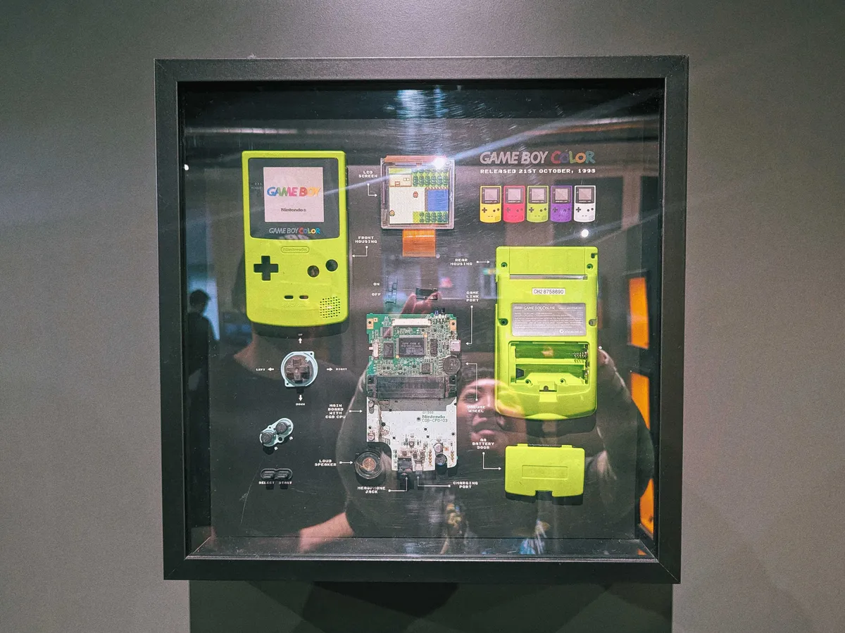 A deconstructed Kiwi green Gameboy Color inside a black frame.