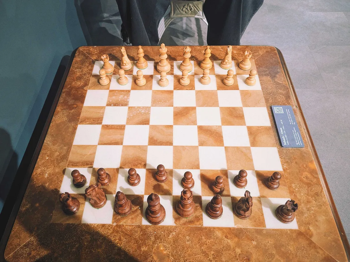 A brown and white marble chess table with dark and light wooden chess pieces.
