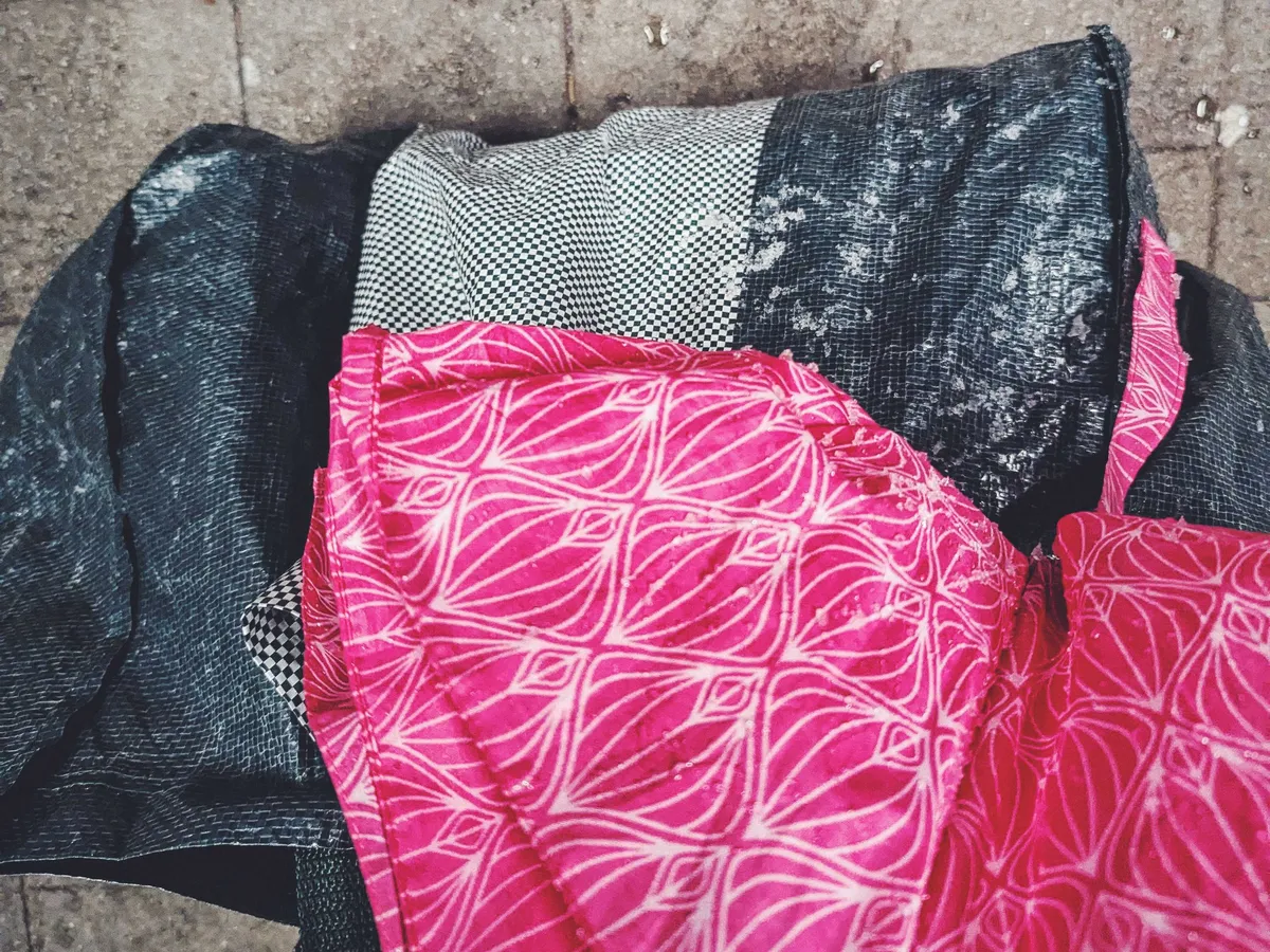 Peige's Ikea bag covered in slushy snow. A bright pink umbrella covered in water drops is also in the frame.