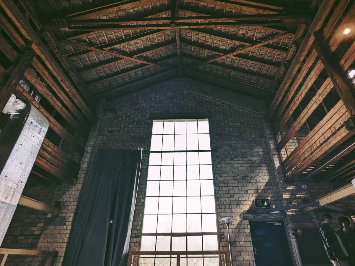 A large, rectangular window stretches from the floor to the ceiling of the building. It is secured within a wall made of concrete bricks.