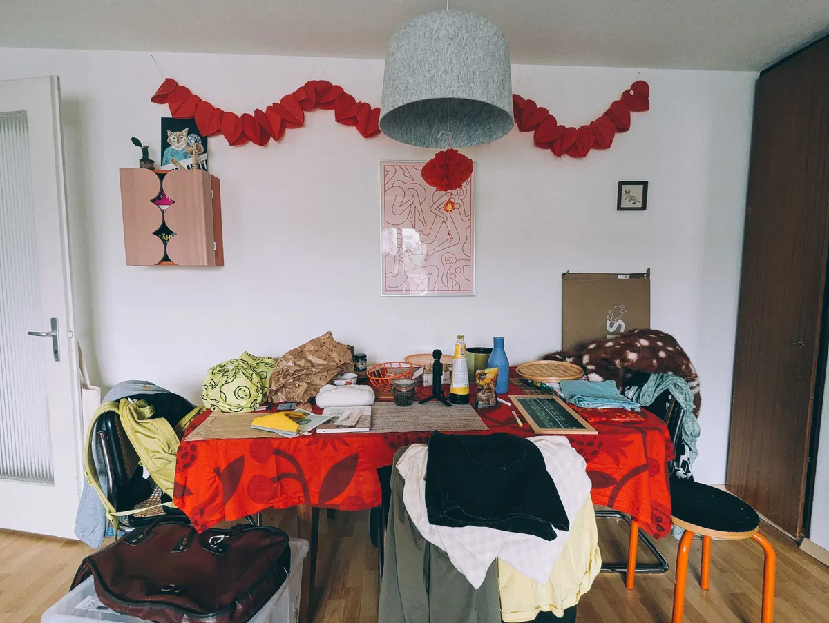 Messy dining area. The chairs are stacked with clothes.