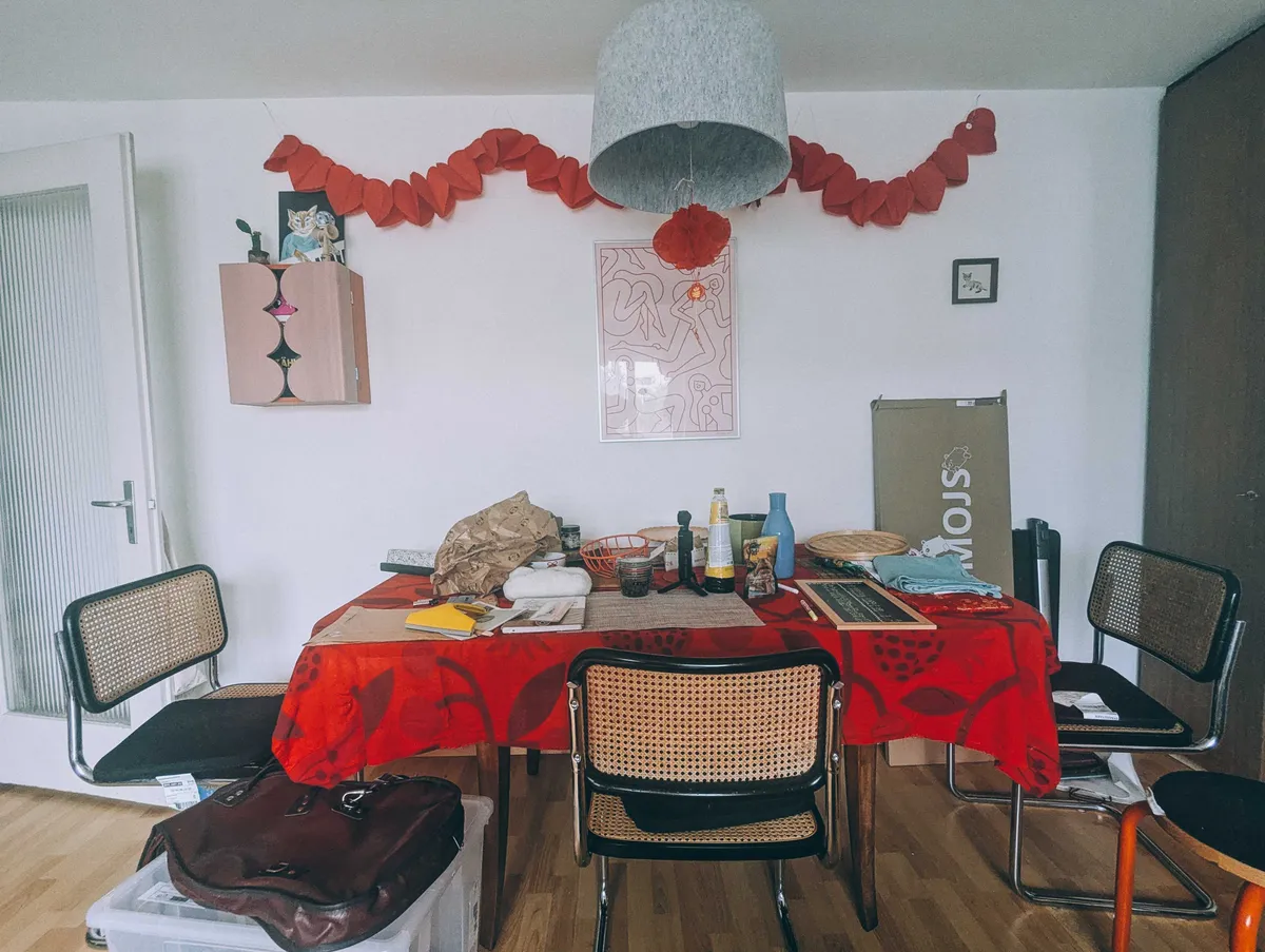 The chairs no longer have clothes on them, but the table is still cluttered.