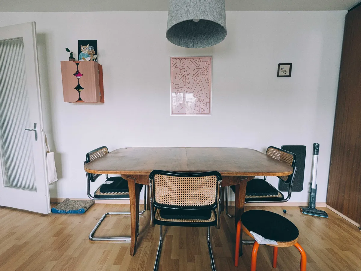 A naked wooden dining table. All the red decor has been removed from the area as well.