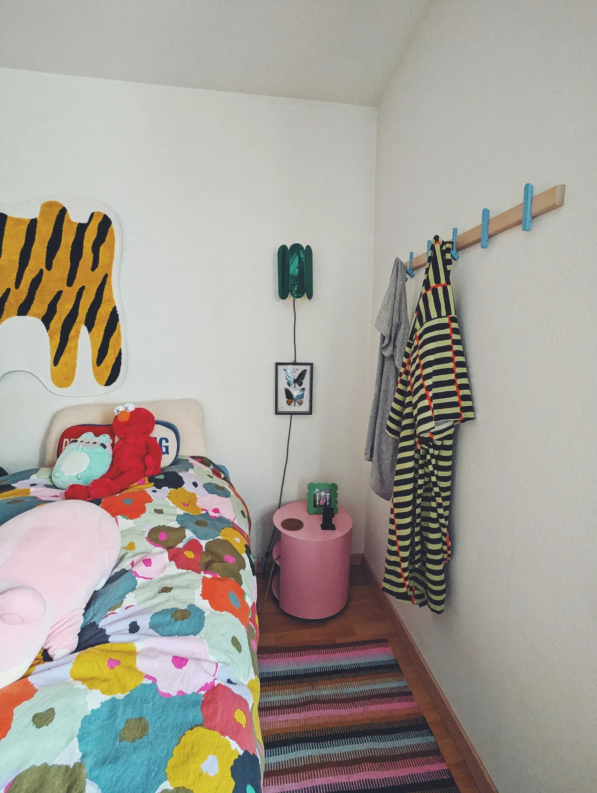 Birch wall rack with blue hooks. There are two articles of clothing hanging from them.