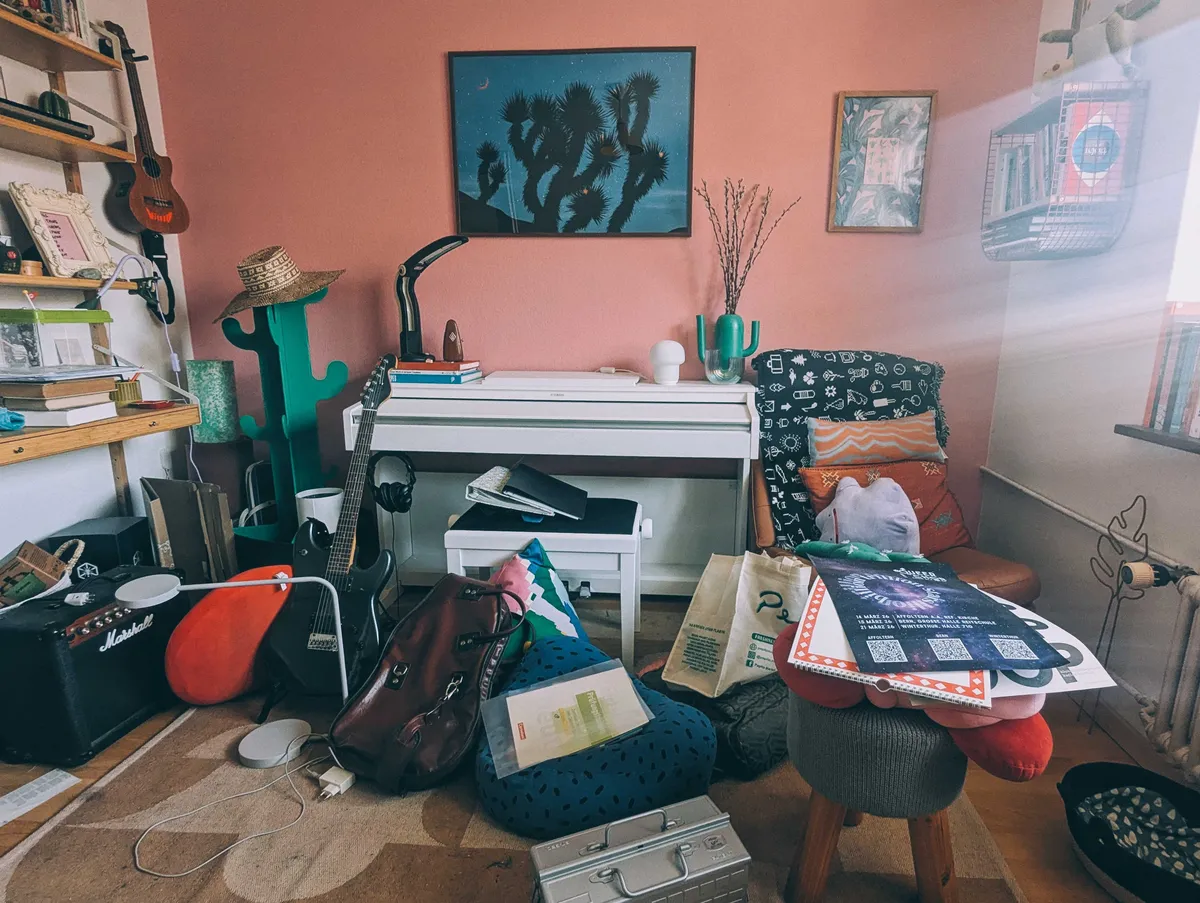 An office with heaps of objects all over the floor, revealing a dirty rug.