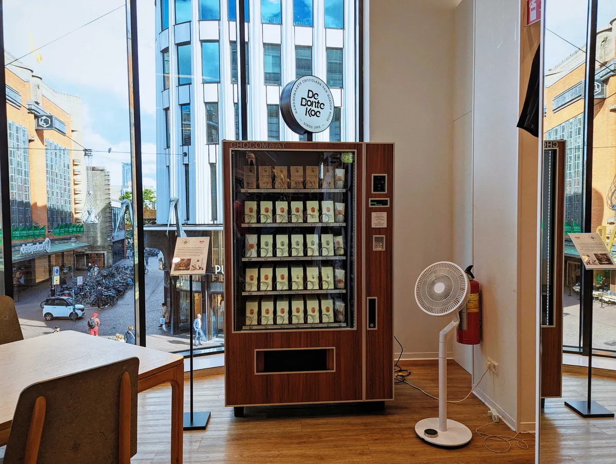 An old-looking, wooden vending machine containing packages of coffee and tea stands in a corner, next to a huge window.
