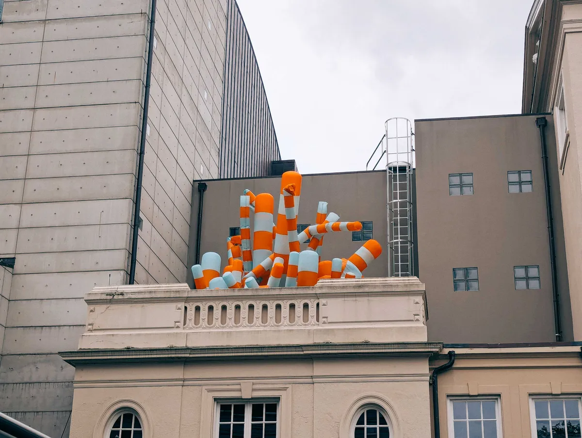 Inflatable orange and white striped cylinders on top of an old building.
