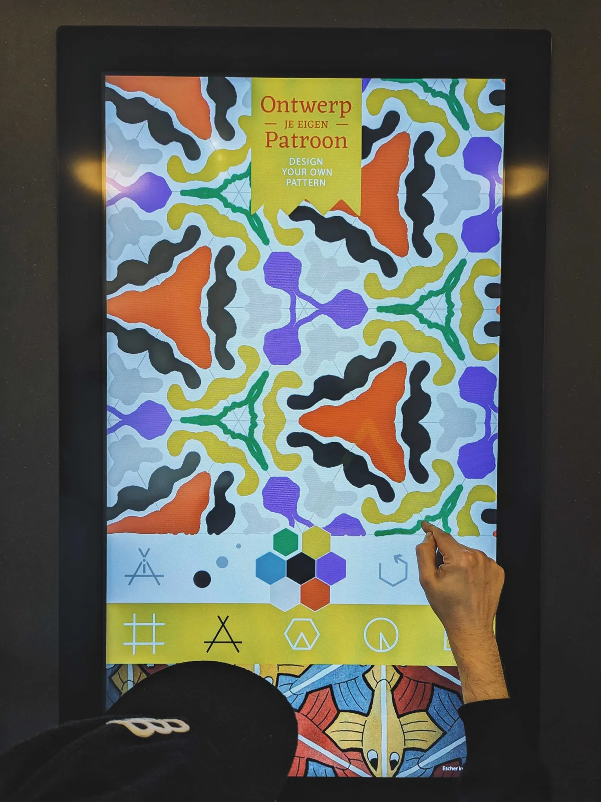 Daniel using his finger to draw on a touch-screen, creating an intricate and colorful pattern.
