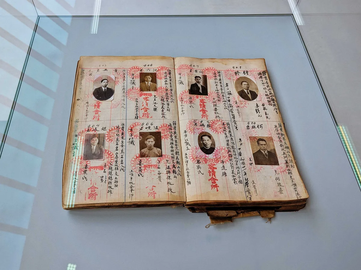 An old, open book containing photos of Chinese immigrants with details written in Chinese.