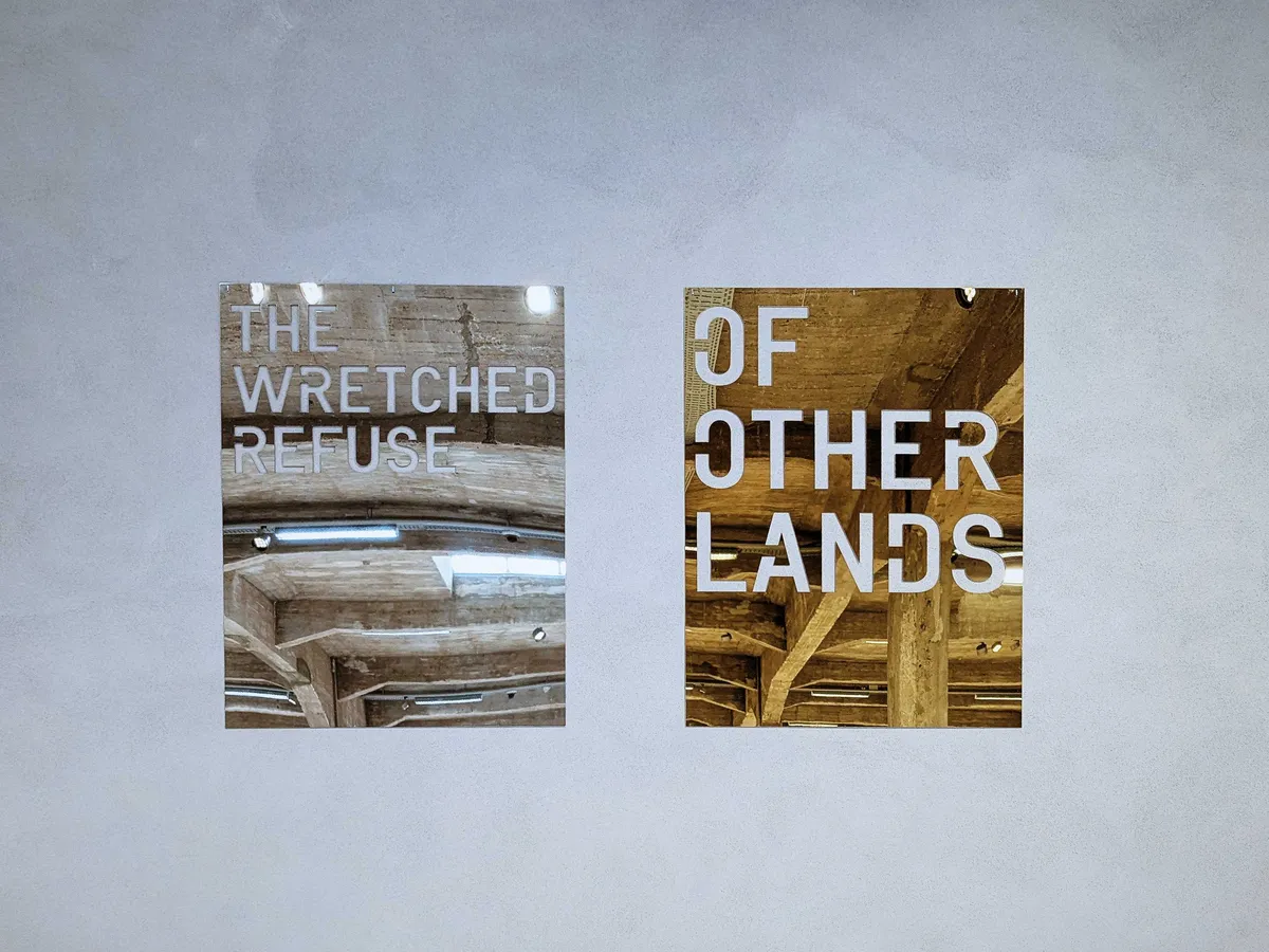 Two mirrored metal plates with cut out typography. One reads, 