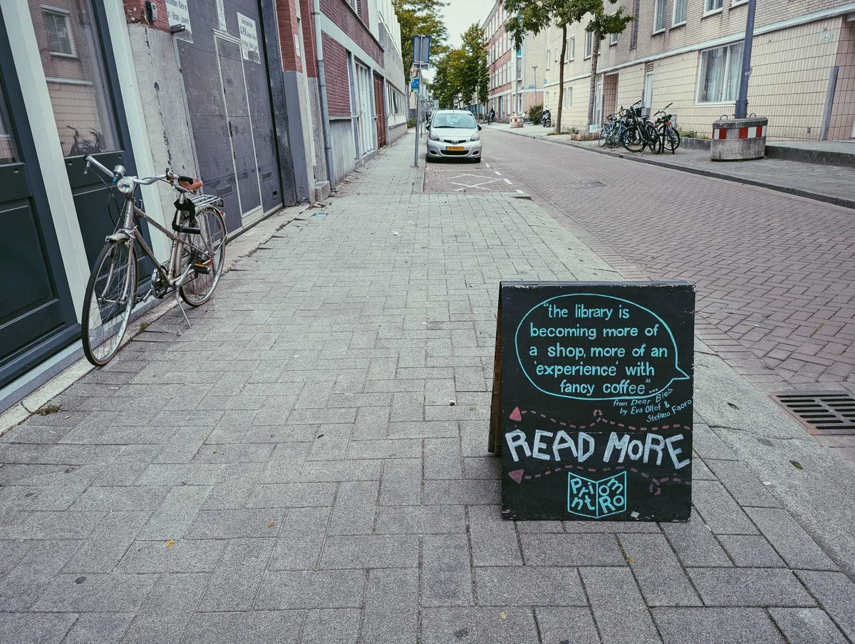 A black sign on the sidewalk that reads, 