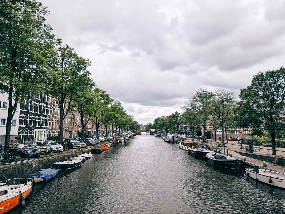 A long canal lined with boats, with brick apartment buildings on either side.