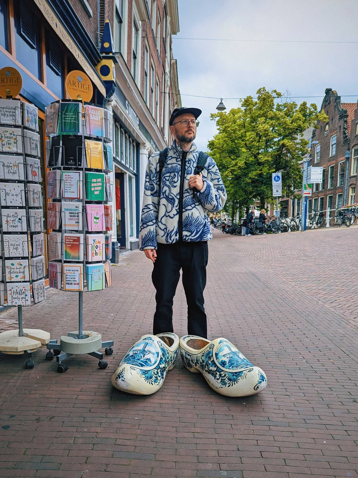Daniel posing in front of giant wooden clogs that have been painted in the style of Delftware.