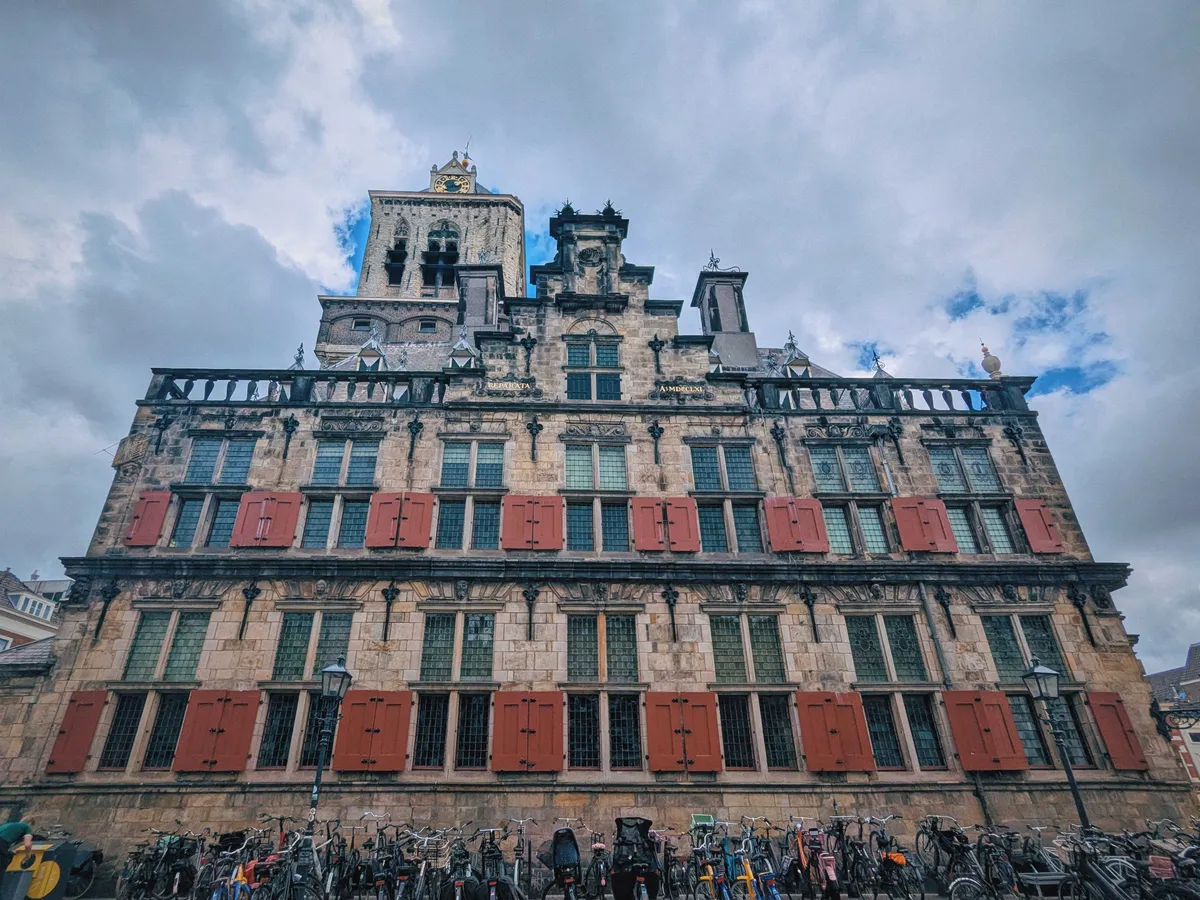 Delft City Hall, featuring a distinctive Renaissance-style facade with red shutters.