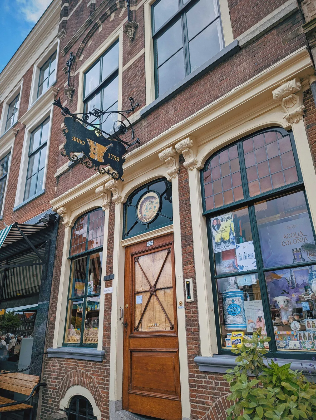 An old-fashioned building with a hanging, ornate black sign with an image of a mortar and pestle and the year 1759.