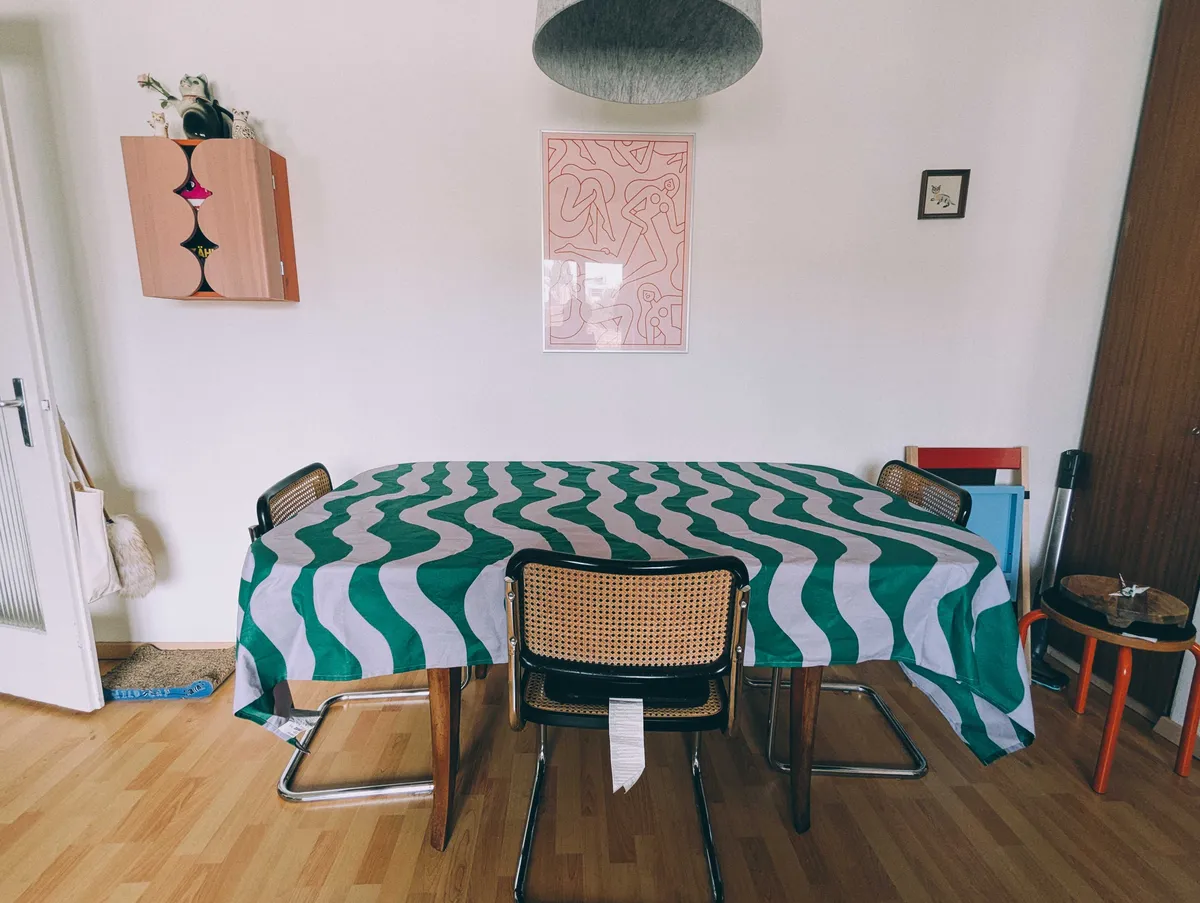 A lavender and green wavy striped tablecloth. All items have been removed from the table.