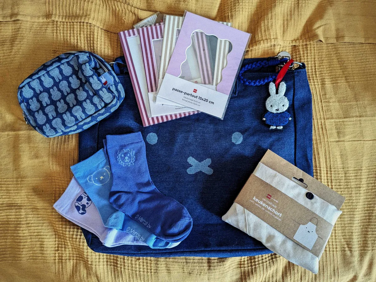 A collection of mostly denim Miffy accessories, such as socks, a large tote bag, and a pencil case. There's also a white Miffy apron, still in its package, and some striped A5 frames and mattes.