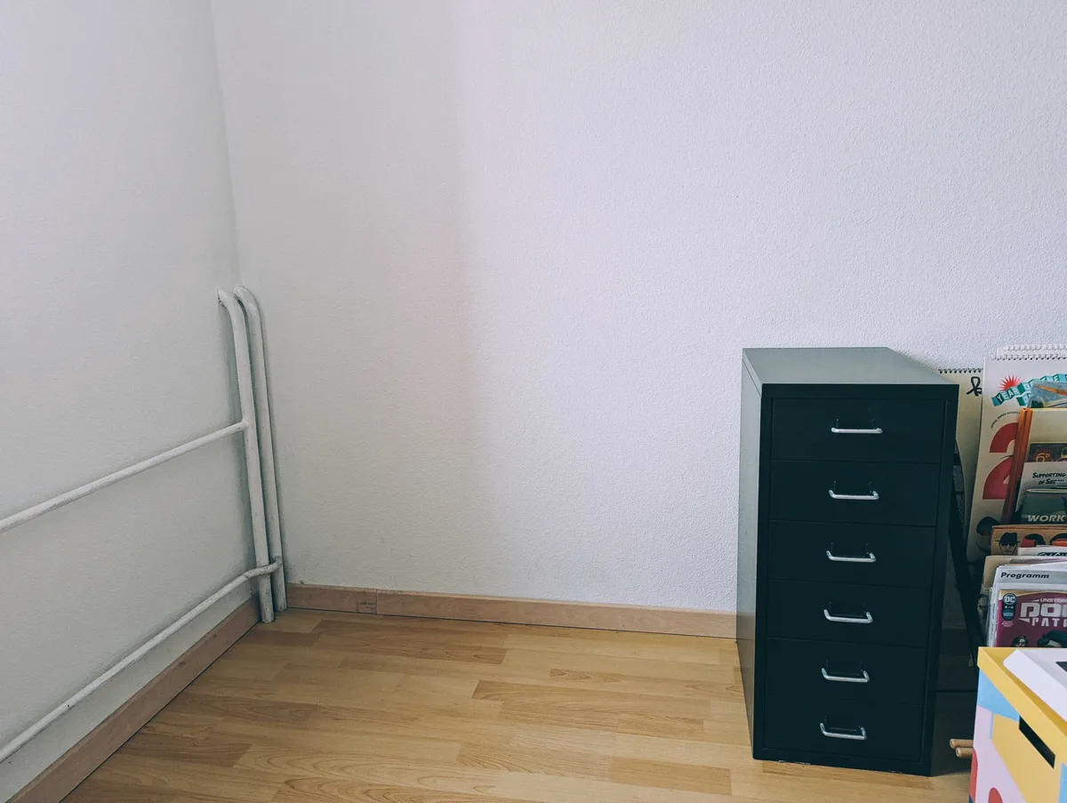 An empty and clean corner, with a black drawer unit marking the 