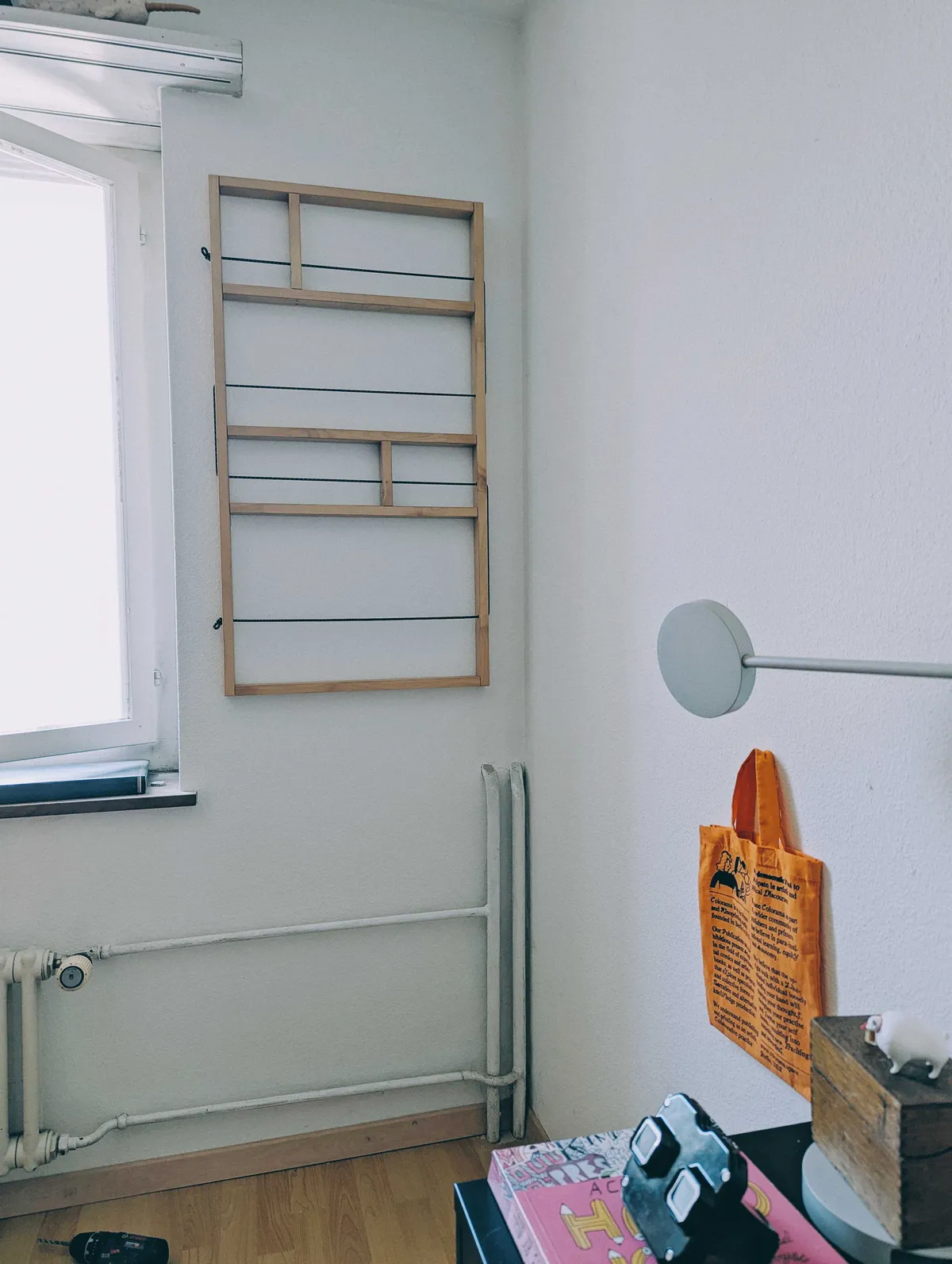 A shelf made of pinewood with black cords weaving through hangs on the wall facing the camera.