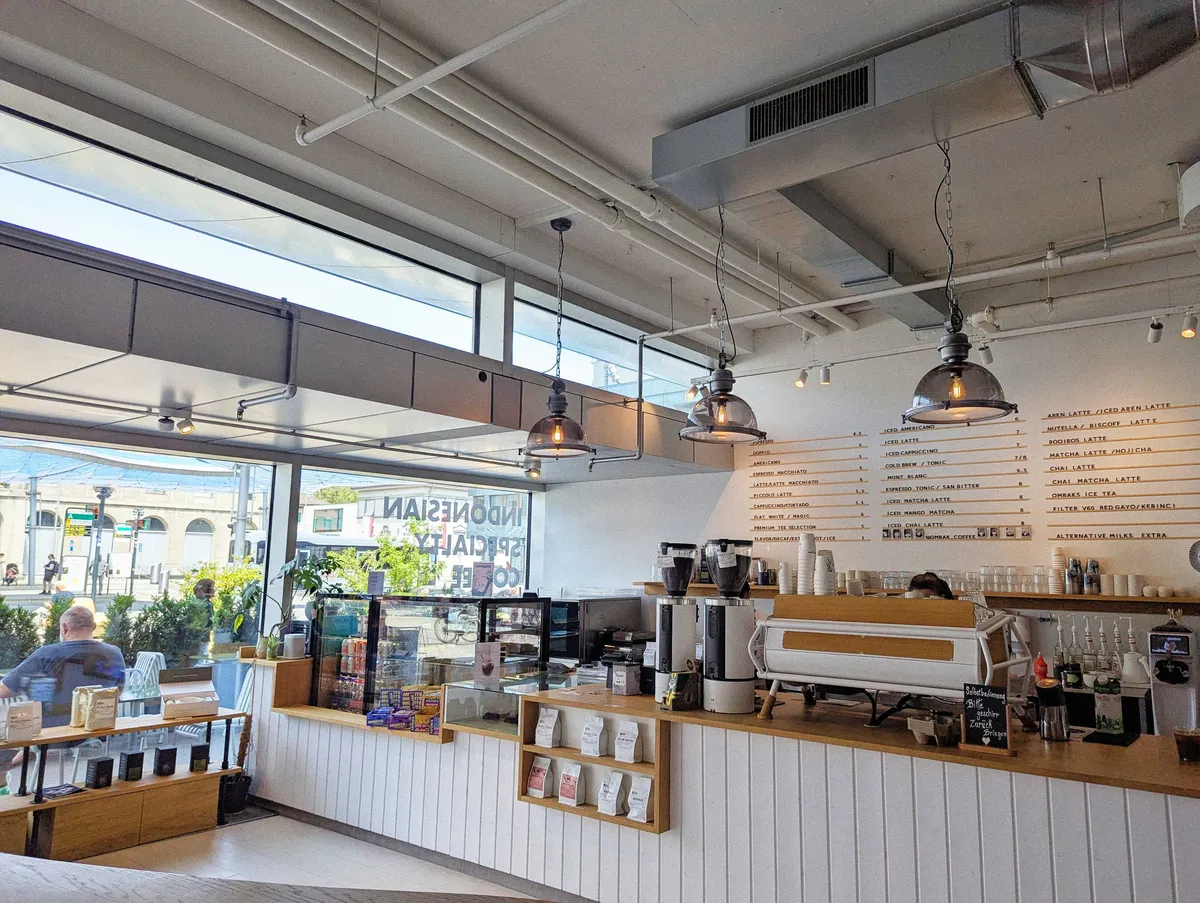 Interior of the coffee shop, featuring the counter and menu on the wall.