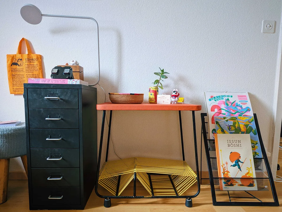 The turntable stand in between a black metal drawer unit and black metal standing vinyl rack.