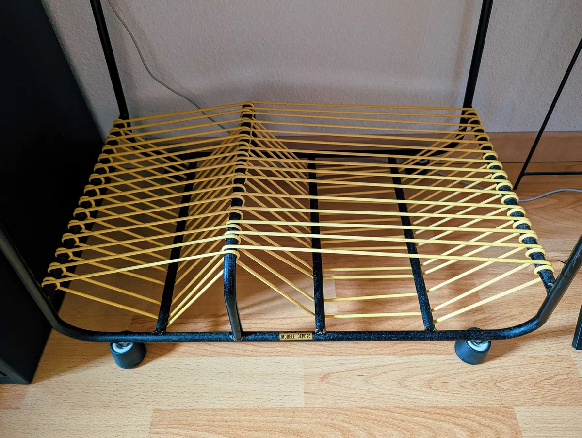 A close-up of the bottom of the table shows some texture on the black metal legs. Plastic black feet have replaced the wheels. The yellow cords look clean.
