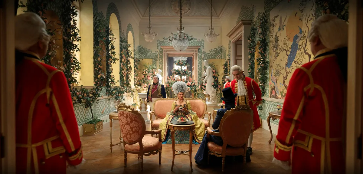 Queen Charlotte seated inside her conservatory room. Its walls are painted yellow with trompe l'œil and decorated with rosebushes.
