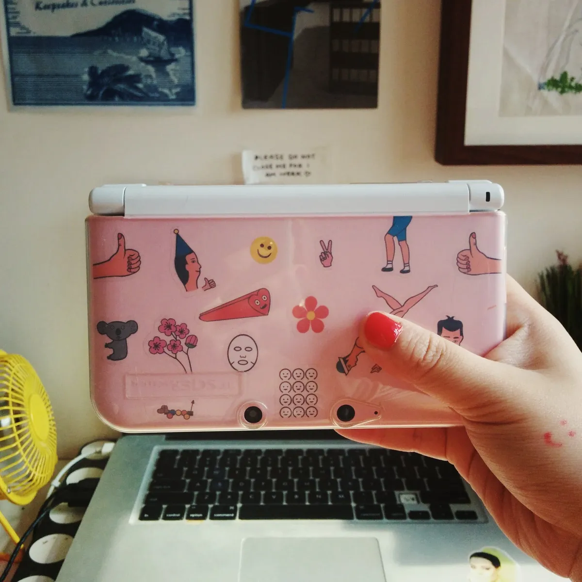 Peige holding a pink Nintendo DS. The cover is covered with cute stickers.