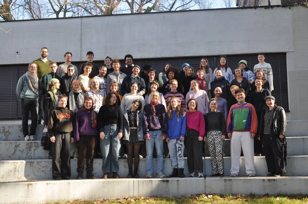 The choir standing outside in four tiered rows. Everyone is smiling widely.